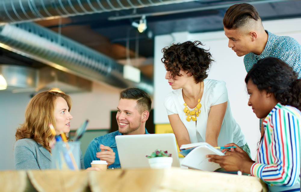 Unposed group of creative business people in an open concept office brainstorming their next project.