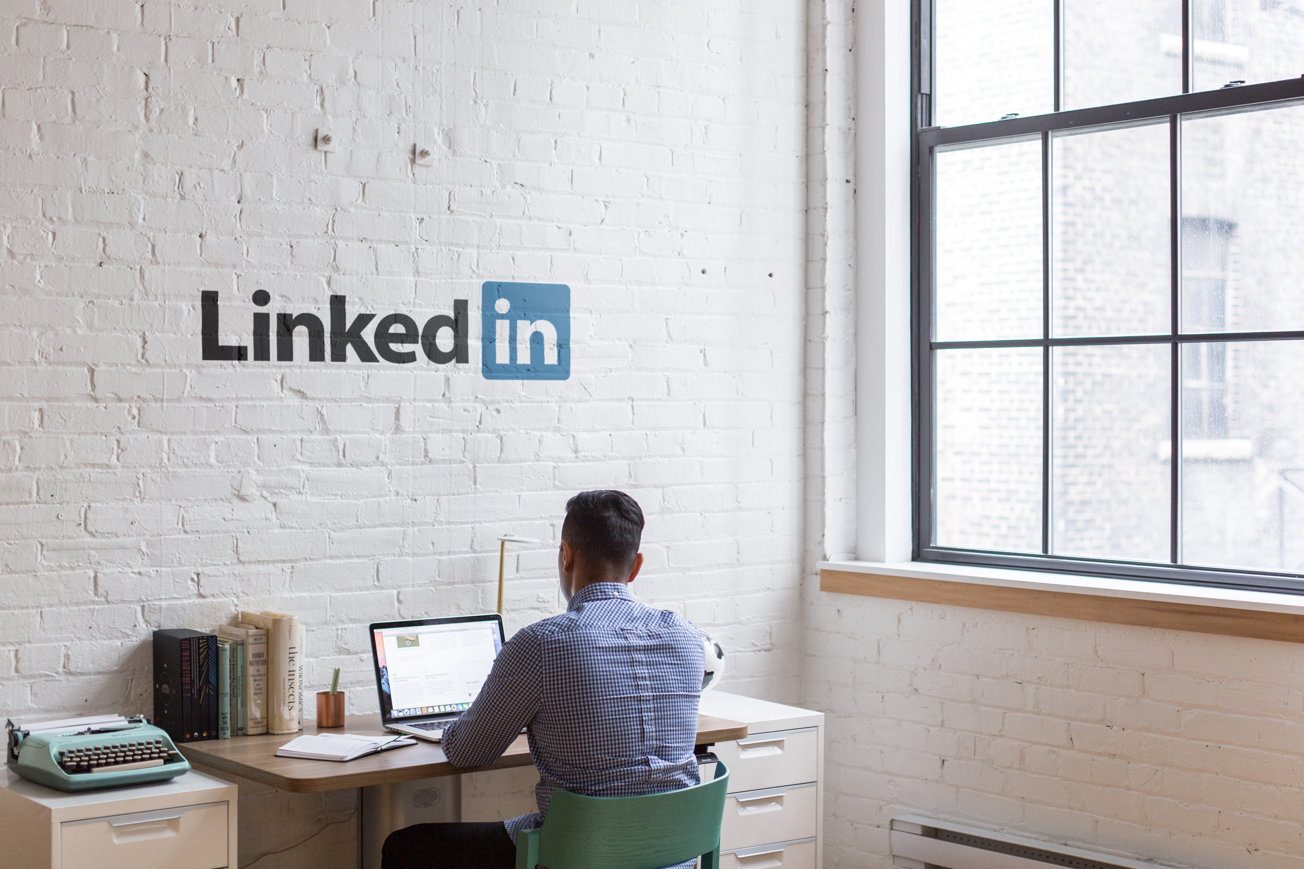 man sitting at a desk facing a white wall that says LinkedIn