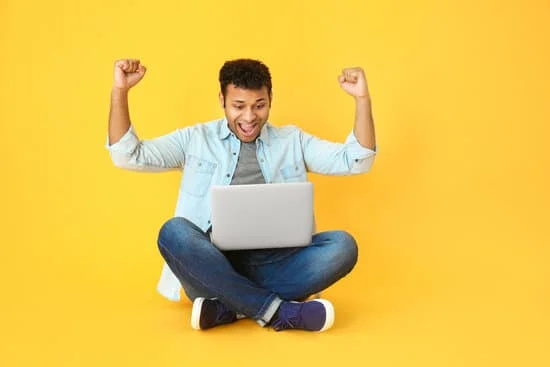 happy man sitting on floor with laptop on his lap